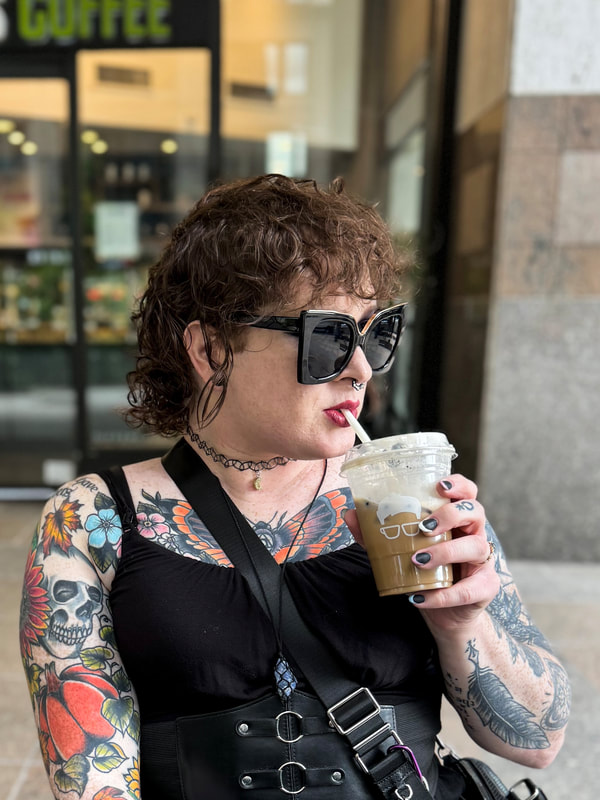 a photo of parker lee sipping and iced latte in front of a coffee shop.